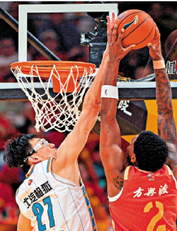 　　圖：北京隊周琦（左）在比賽中封蓋浙江隊球員奈特的扣籃。\新華社