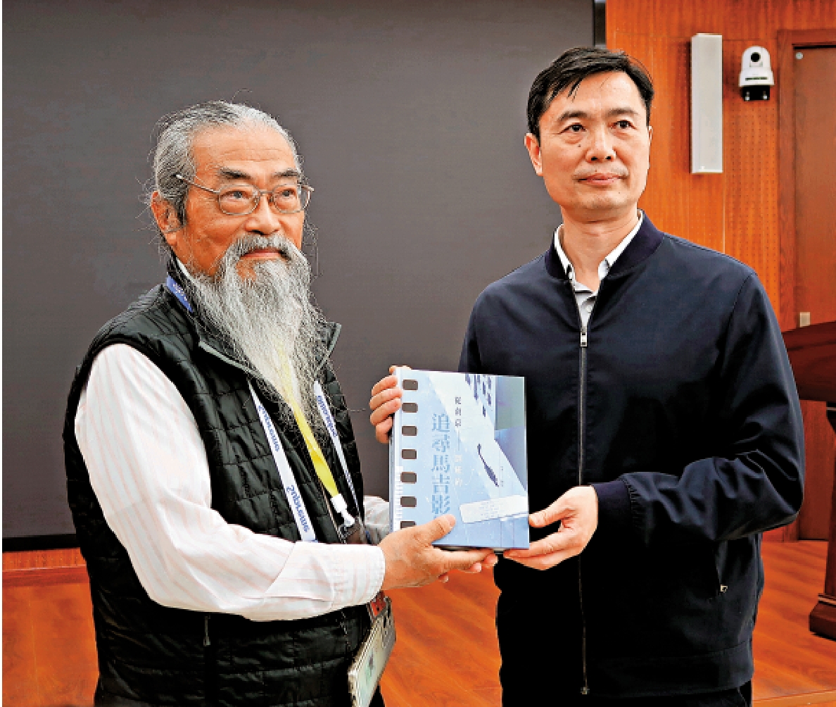 圖:邵子平(左)向南京師範大學附屬中學黨委書記徐飛贈送《追尋馬吉影像》。\大公報記者陳旻攝