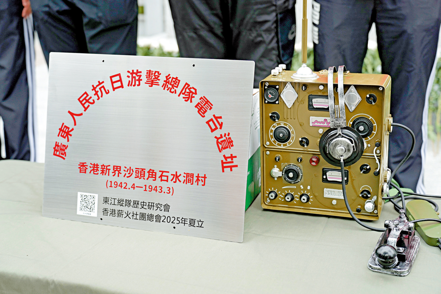 　　圖：昨日儀式上豎立電台遺址標誌牌，旁為當年抗日游擊隊使用的同款電台設備。\大公報記者何嘉駿攝