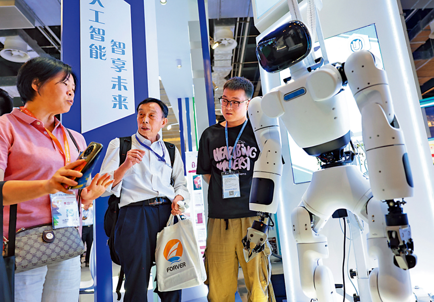 　　圖：6月11日，在上海舉行的一個展覽上，參觀者在一個機器人旁交流討論。\新華社