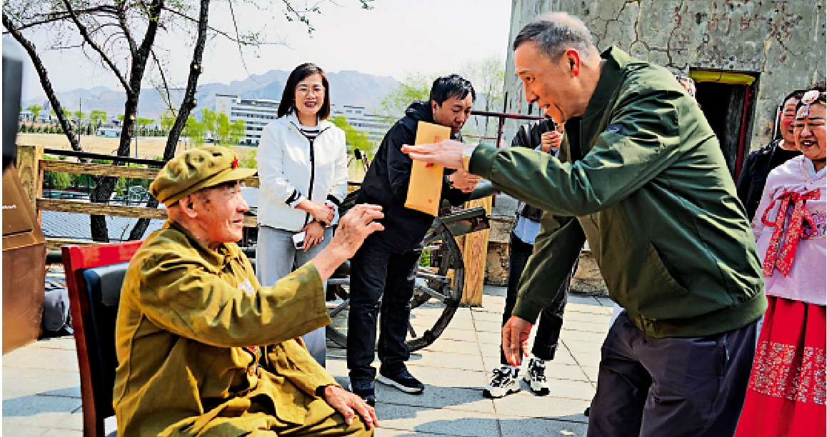 　　圖：梁興初之子梁曉東從抗美援朝老兵劉吉慶手裏接過《致軍長兒子的一封信》。\大公報記者林凱攝