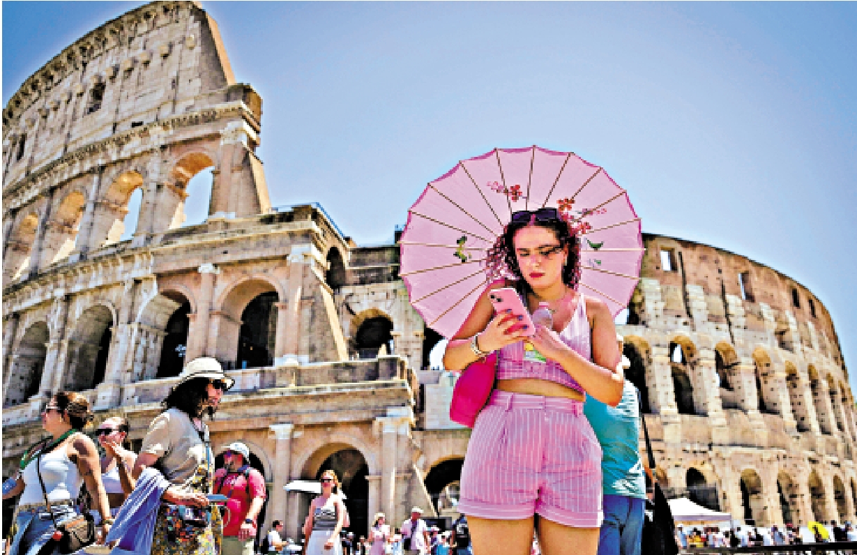 　　圖：一名女子在意大利羅馬競技場附近撐着傘遮擋猛烈的陽光。\法新社