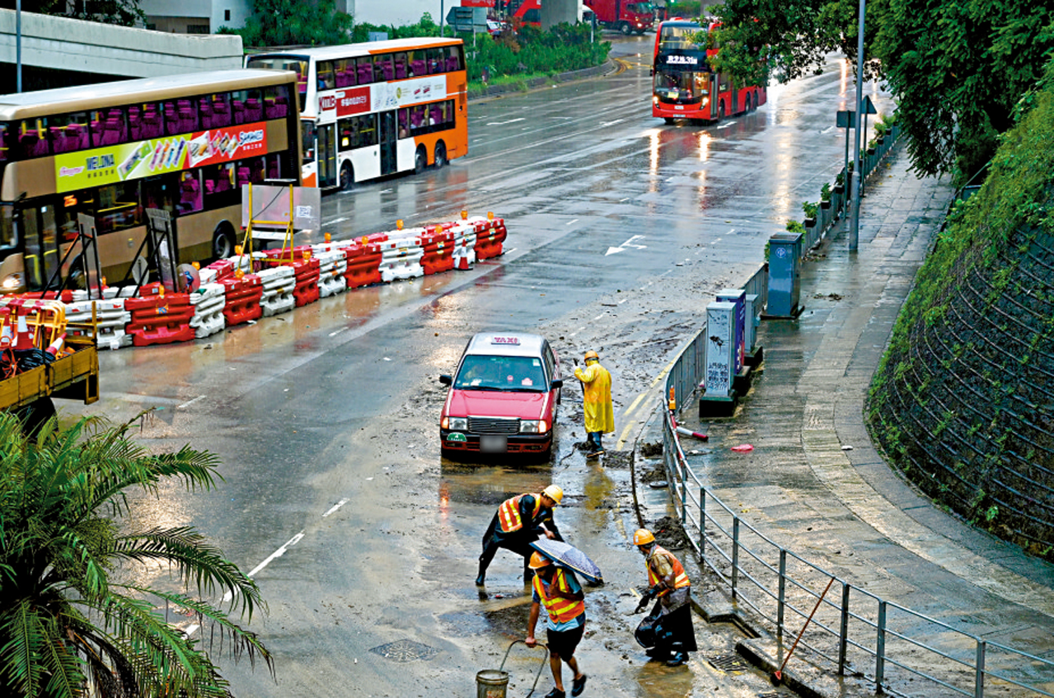 　　圖：8月5日香港「黑雨」期間，工作人員在葵涌道清理路面雜物。\中新社