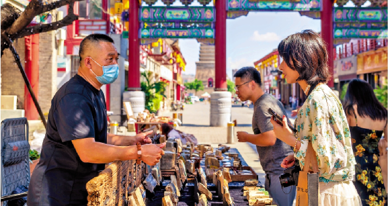 　　圖：在「三燕故都」舊城址慕容街，木化石繪攤主的創意吸引學子們佇足。\大公報實習記者馬見穎攝