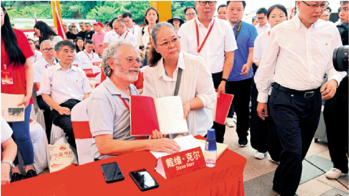 　　圖：戴維·克爾為嘉賓在《克爾日記》上簽字並合影留念。\大公報記者帥誠攝