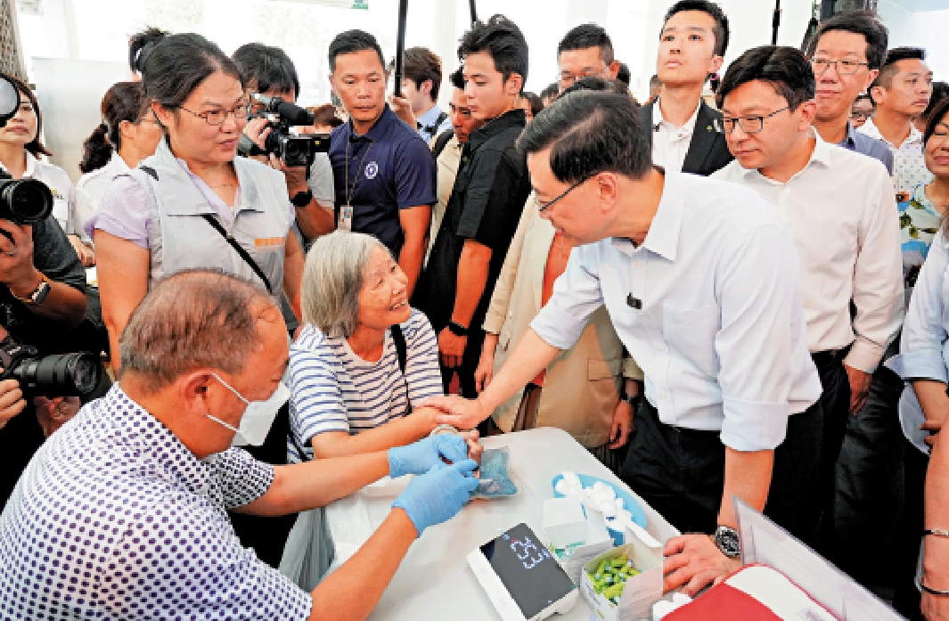 　　圖：李家超向牛頭角下邨居民問好，其右為勞福局局長孫玉菡。\大公報記者何嘉駿攝