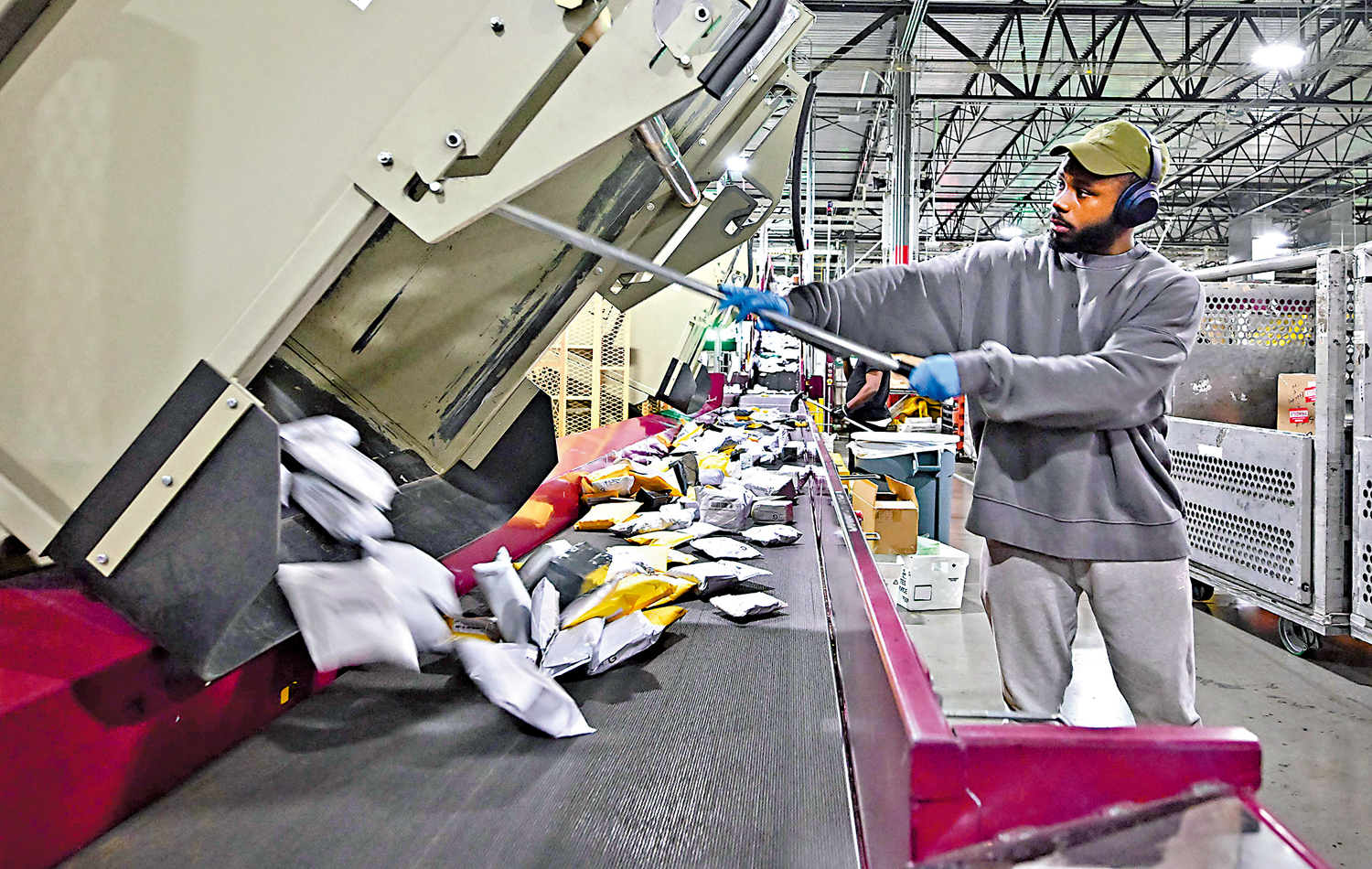 　　圖：美國郵政局洛杉磯中心的郵政工作人員正在分揀郵件和包裹。\法新社