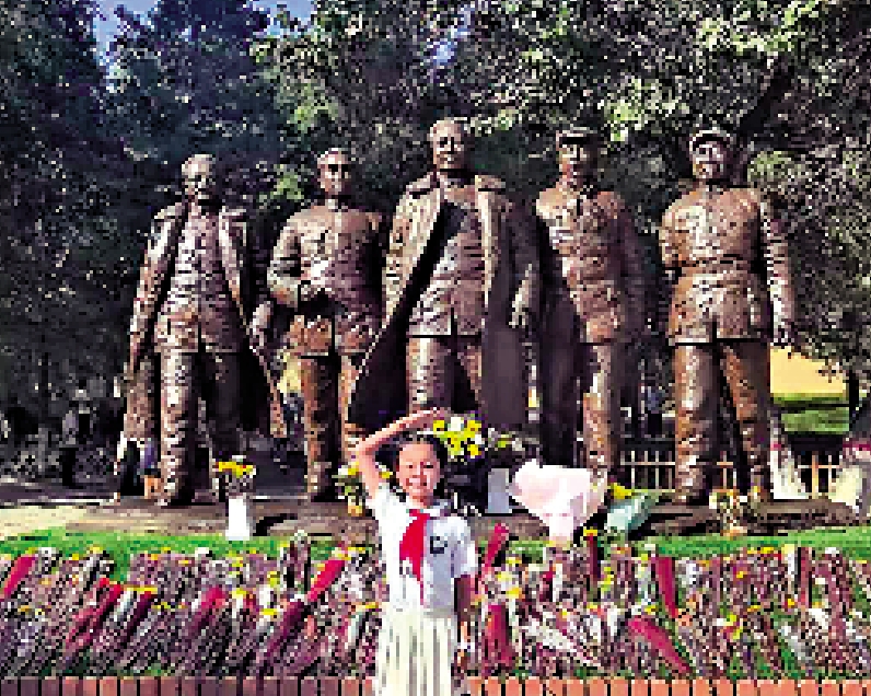 　　圖：這是位於延安棗園的「五大書記」銅像，左起為任弼時、周恩來、毛澤東、劉少奇和朱德。圖為小朋友在五大書記銅像前戴着紅領巾，敬少先隊禮。\大公報記者蘇雨潤攝