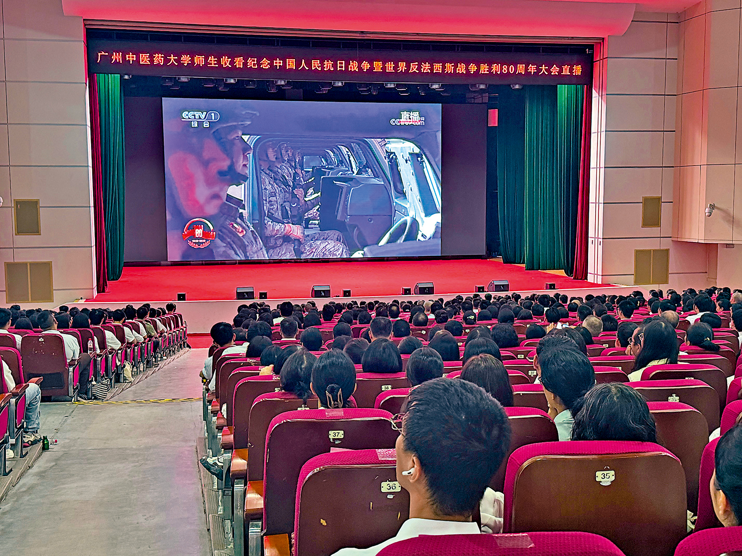 　　圖：廣州中醫藥大學組織1600餘名師生齊聚大學城校區大會堂主會場，一同觀看閱兵儀式直播。\大公報記者盧靜怡攝