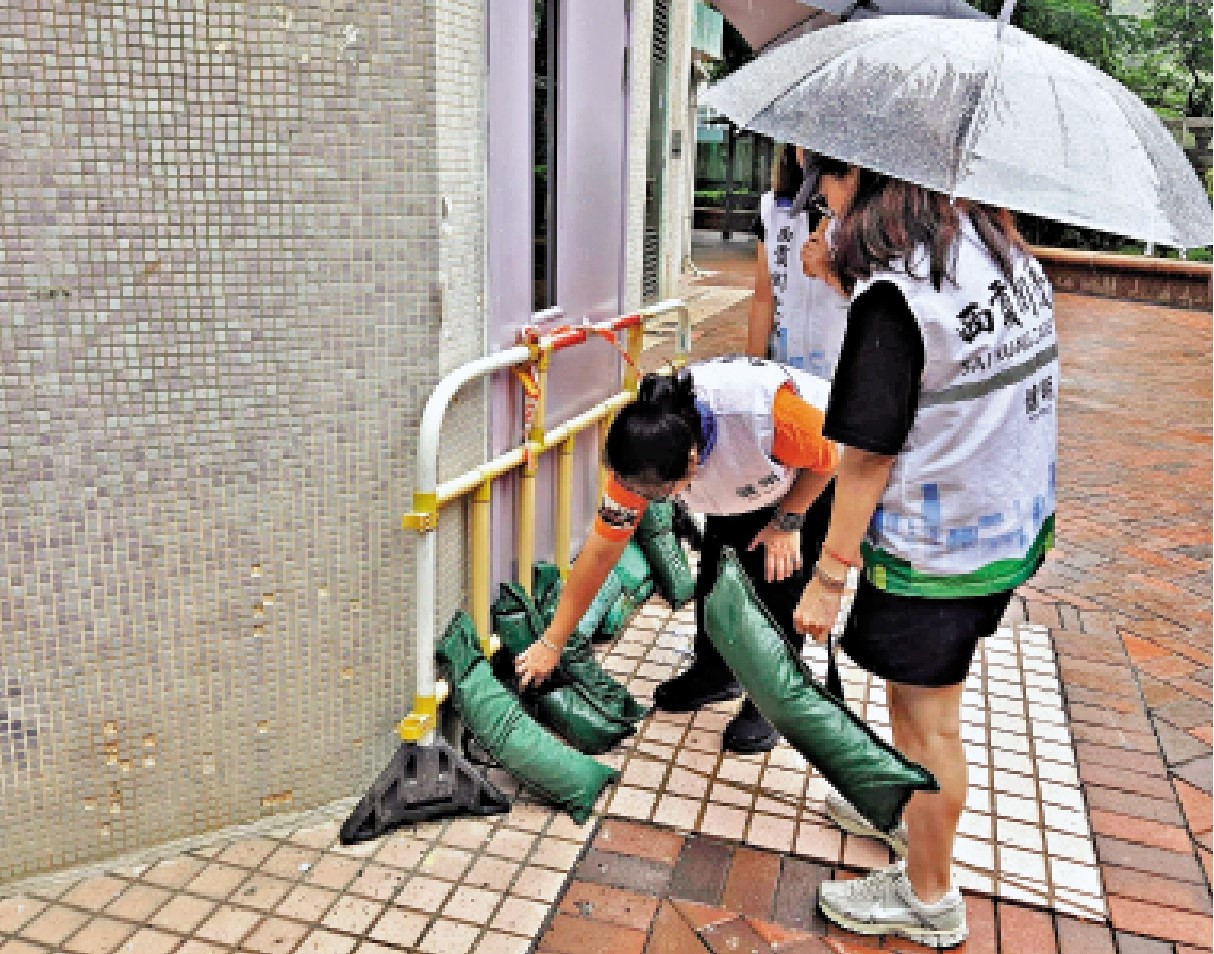 　　圖：西貢區健明關愛隊於打風前夕巡區，使用沙包和鐵馬加固健暉樓防煙門，防止被吹毀。