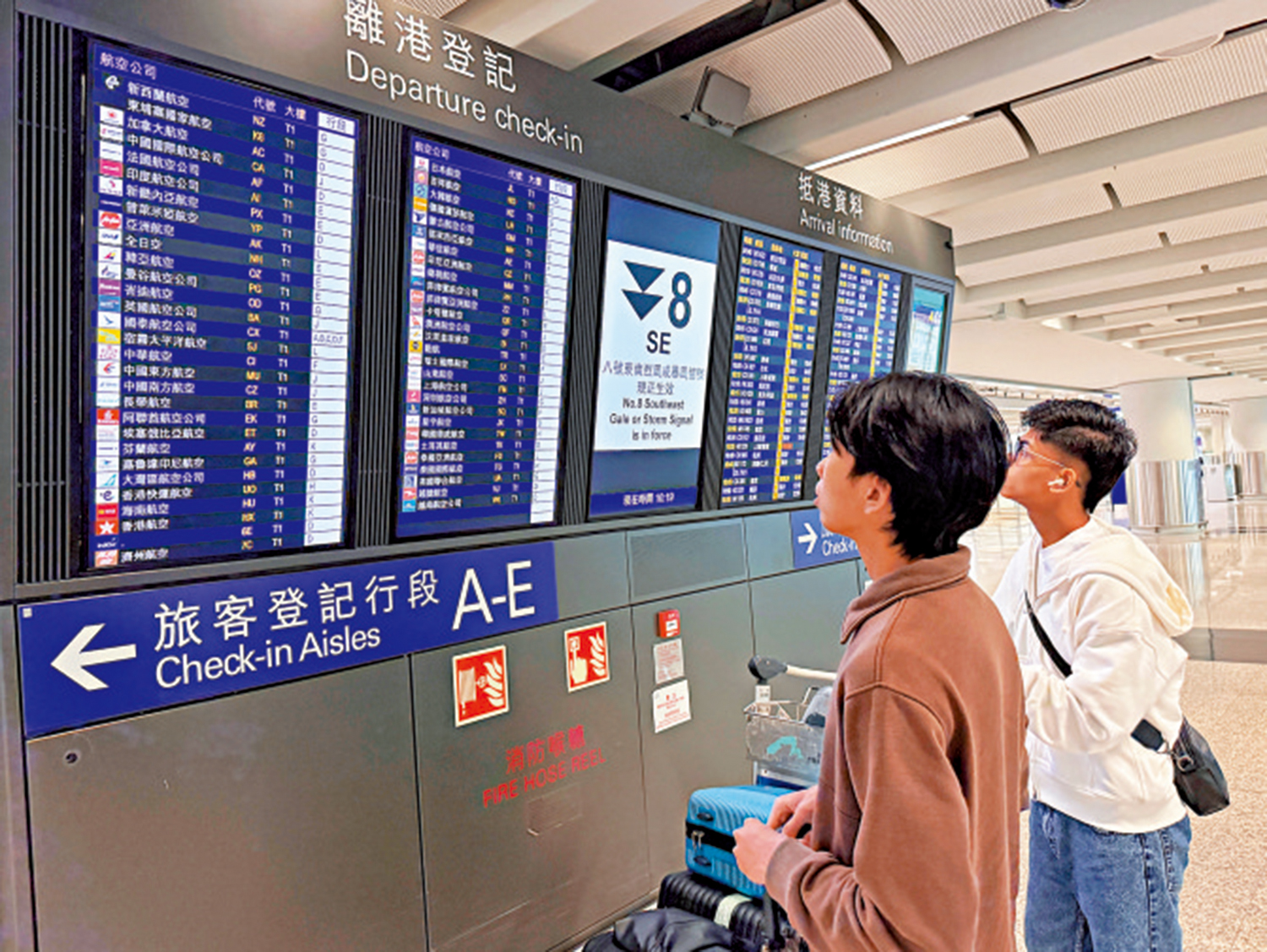 　　圖：在機場，旅客們在顯示板前留意航班的最新安排。\中通社