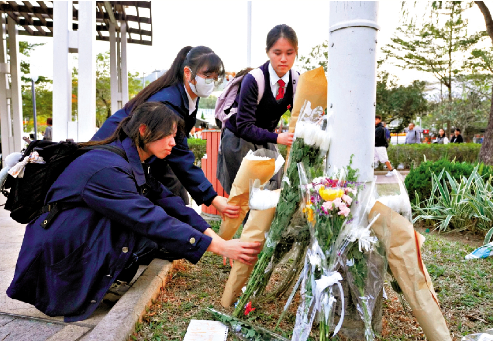 　　圖：陳同學（左）昨日與同學攜帶鮮花悼念逝者。\大公報記者蔡文豪攝