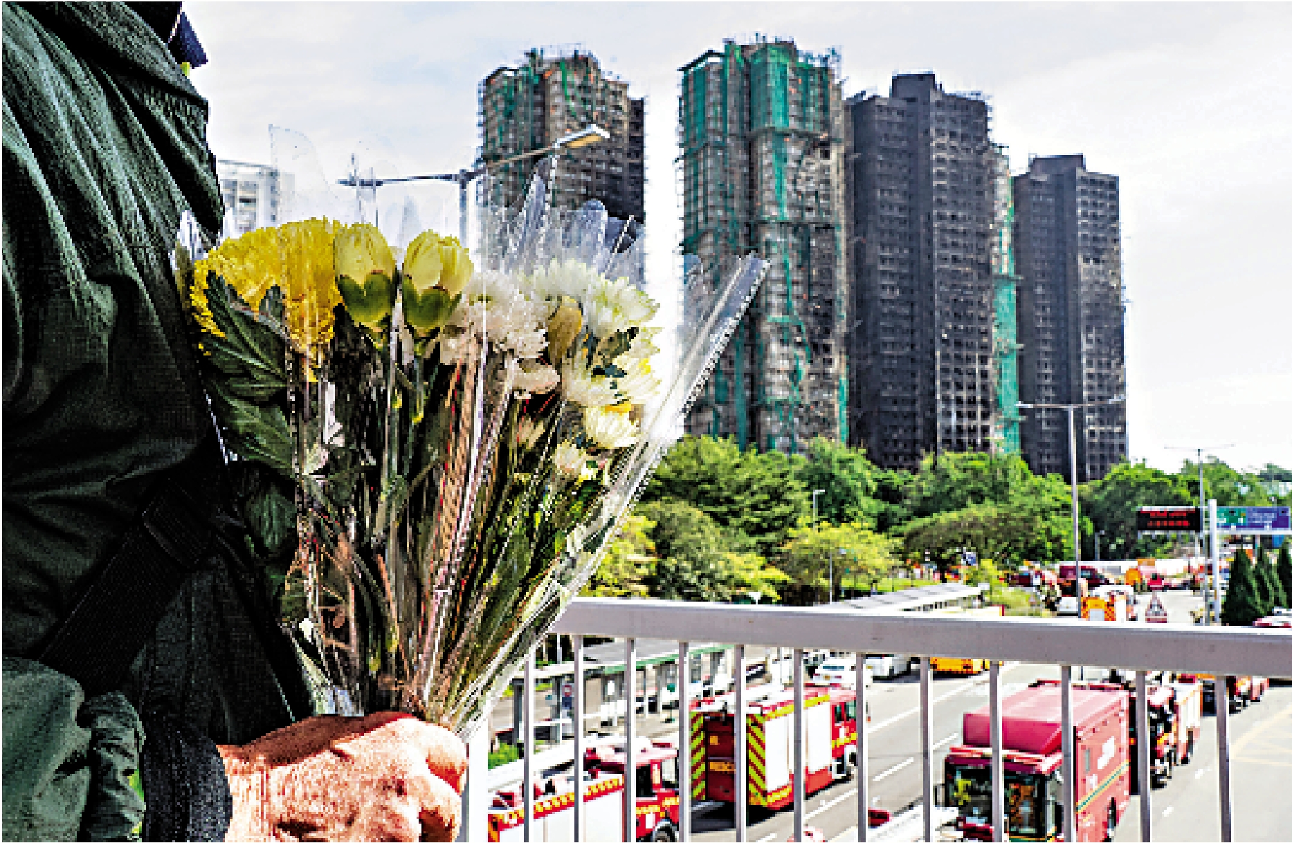 　　圖：11月28日上午，一位市民攜帶花束在香港大埔宏福苑火災現場附近表達哀思。\中新社