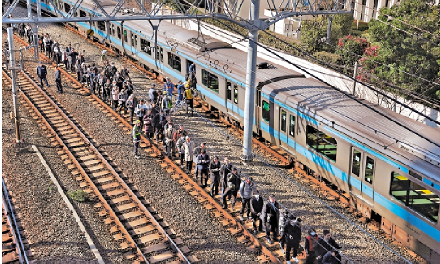 　　圖：日本東京JR鐵路發生停電故障，乘客從鐵軌上撤離，步行前往田町站。\路透社