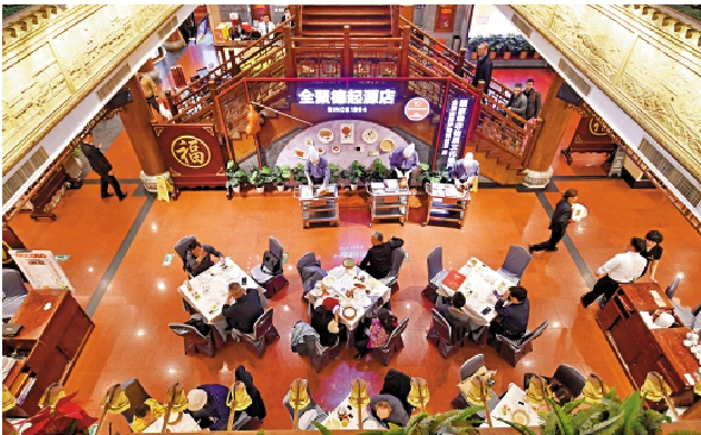 　　圖：遊客在前門大街老字號全聚德起源店內品嘗烤鴨。\新華社