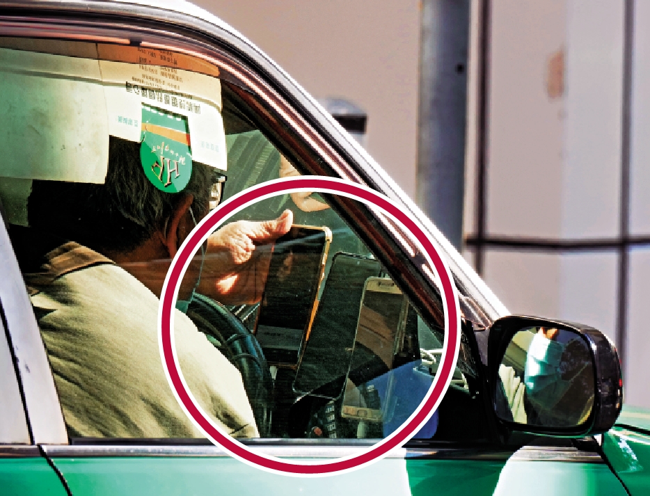 　　圖：昨日仍有的士司機違規在前方放置3部手機（紅圈示）。\大公報記者黃洋港攝