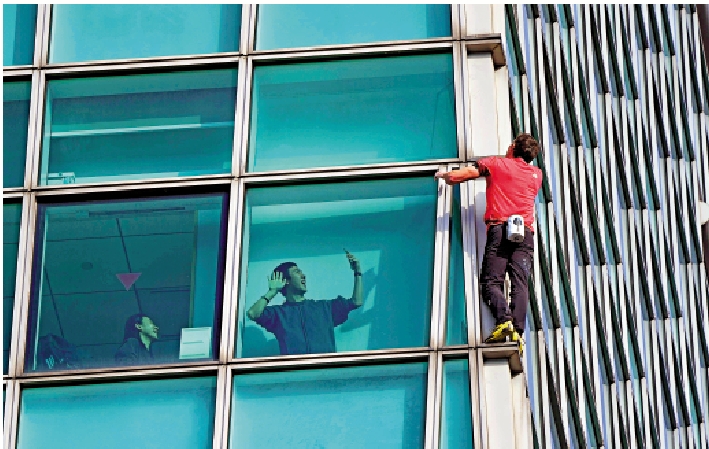 　　圖：美國攀岩運動員霍諾德25日攀登台北101大樓，一名民眾在大樓內拍攝。