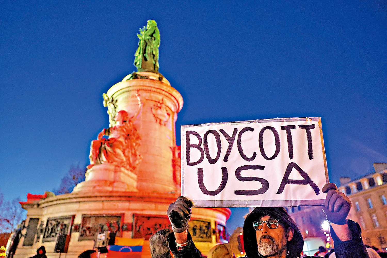 　　圖：一名法國示威者3日在巴黎舉起「杯葛美國」的標語牌。\路透社