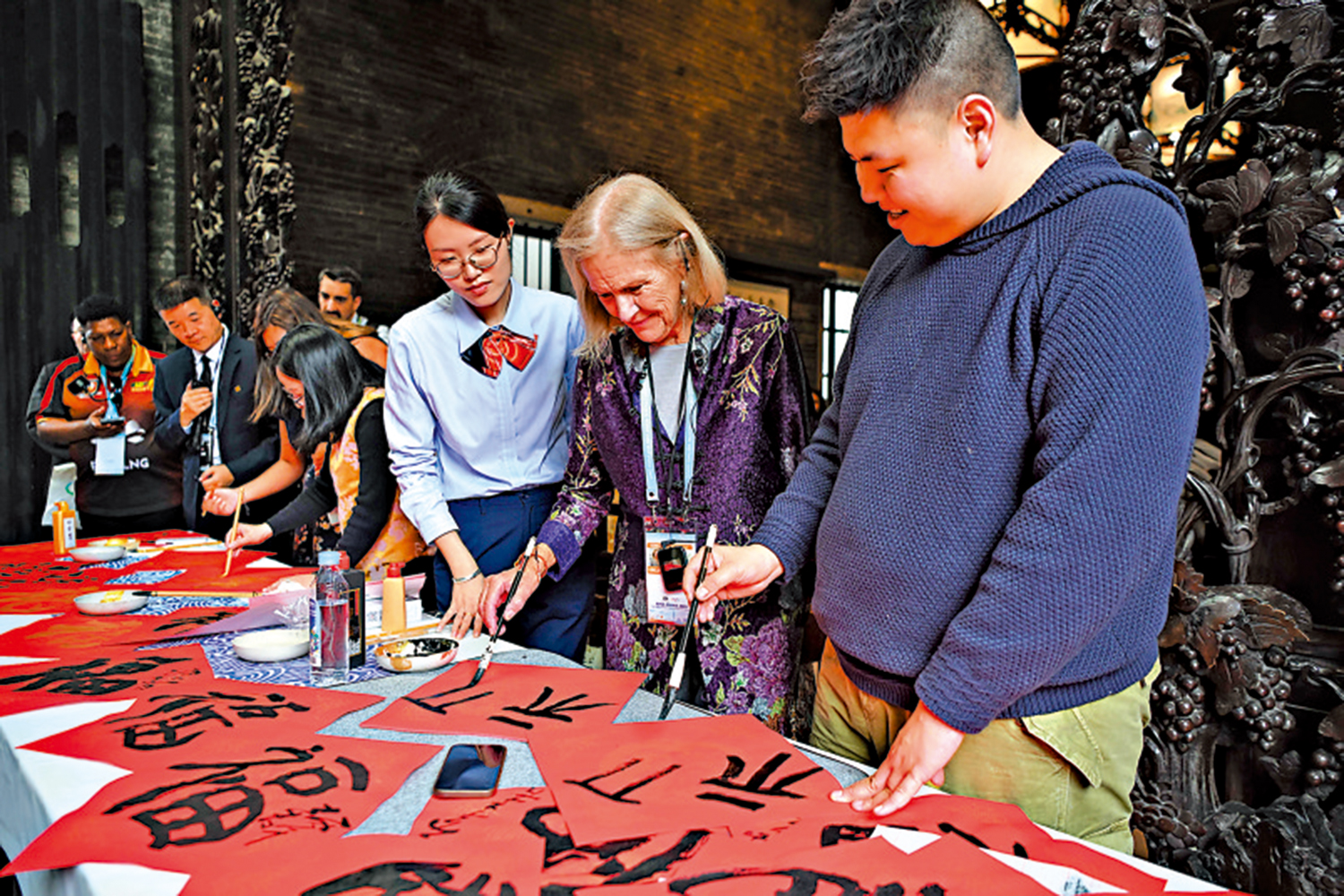 　　圖：2月6日，參與高官會及相關會議的部分與會代表在廣州陳家祠體驗中國書法。\新華社