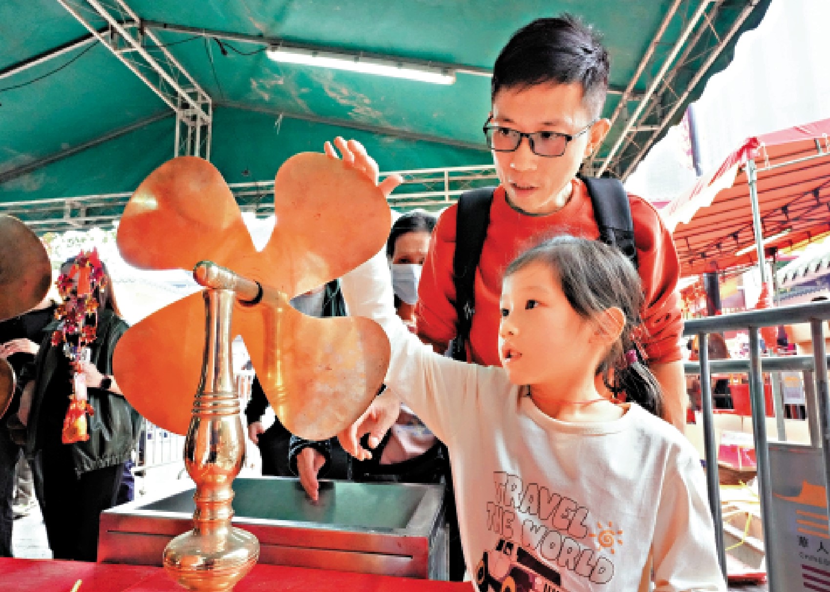 　　圖：家長帶子女到車公廟轉風車，祈願快高長大。\大公報記者黃洋港攝