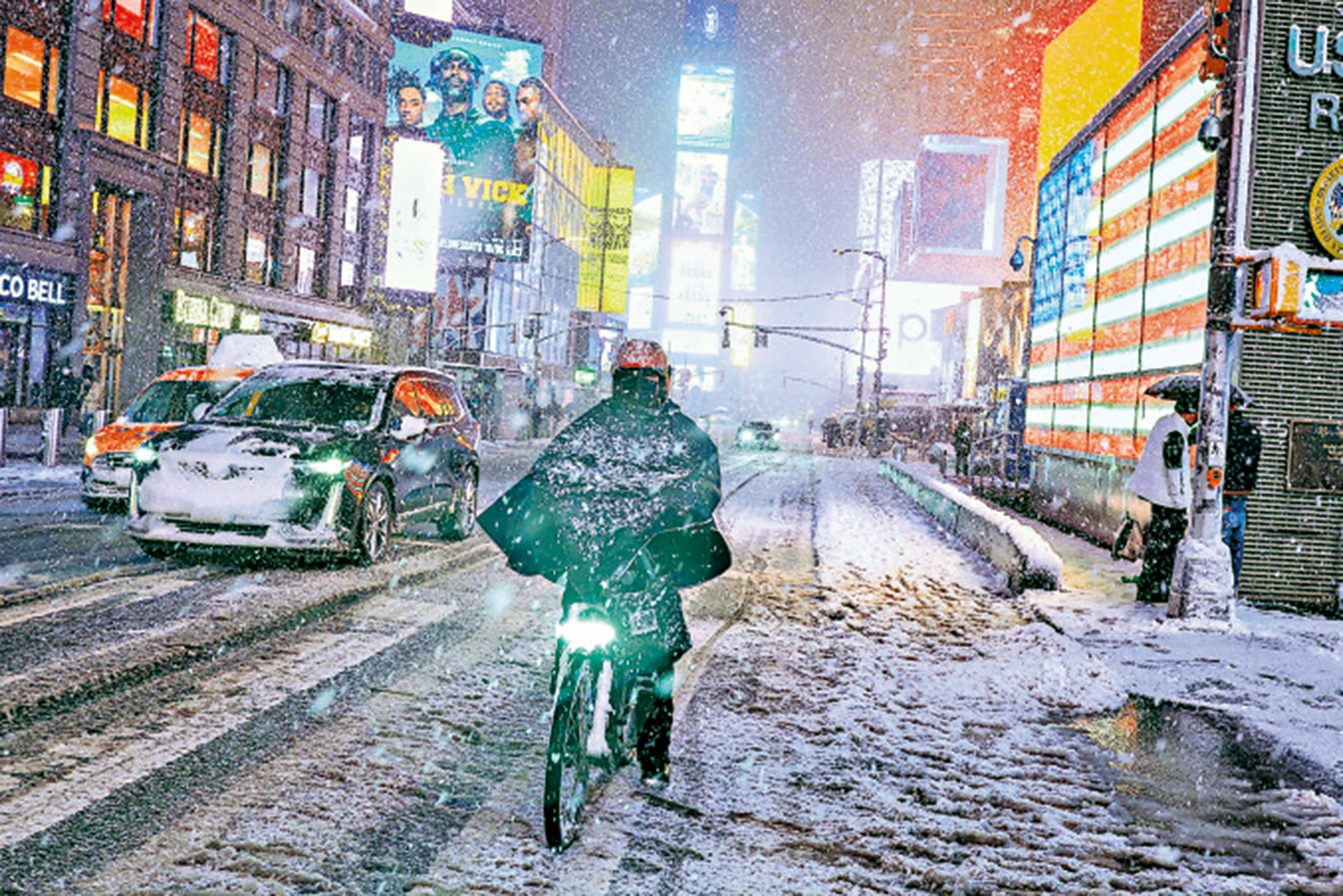 　　圖：暴風雪侵襲紐約，一名行人22日冒雪騎自行車穿越時報廣場。\法新社