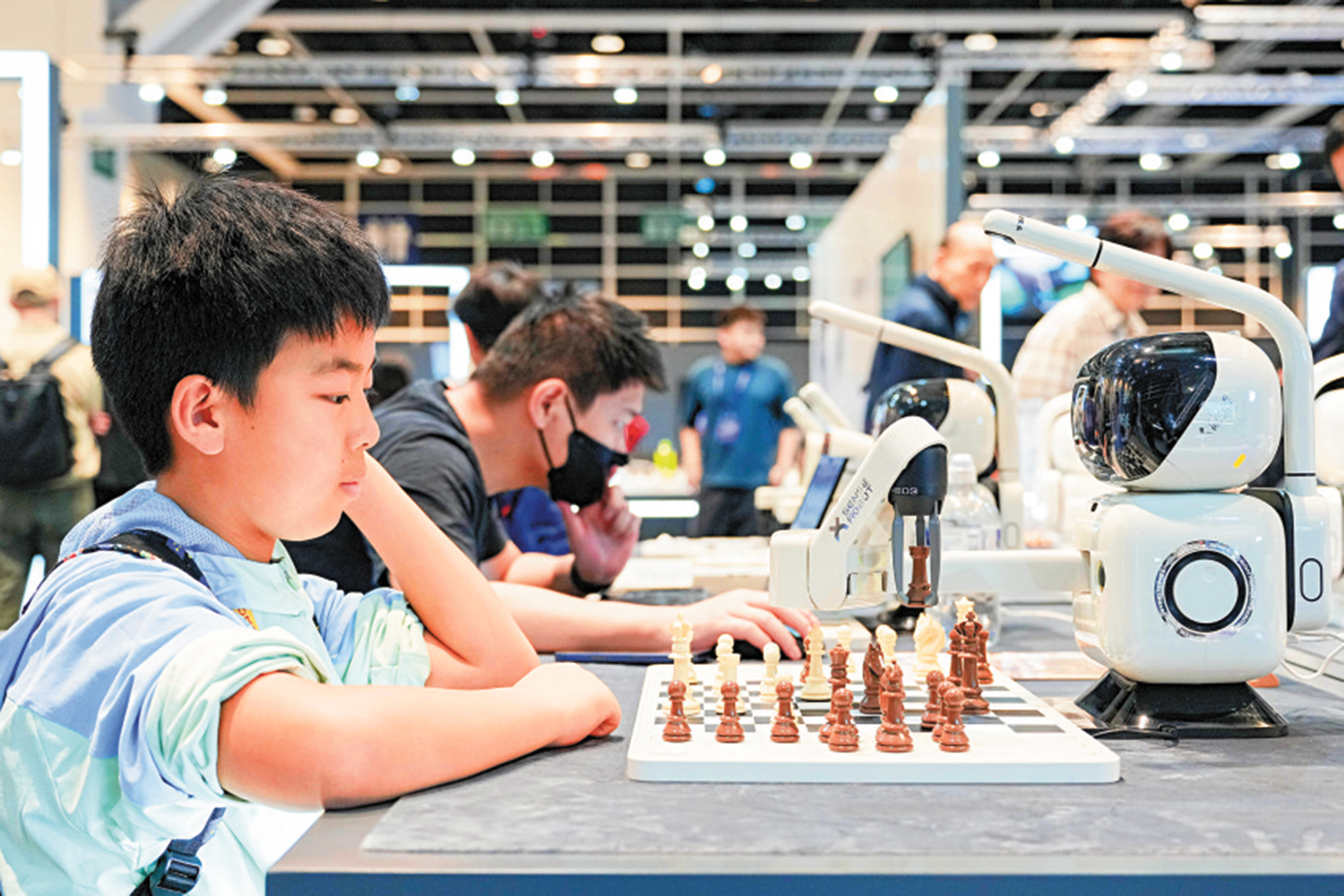 　　圖：在2025首屆香港國際AI藝術節，一名兒童與機器人對弈。\新華社