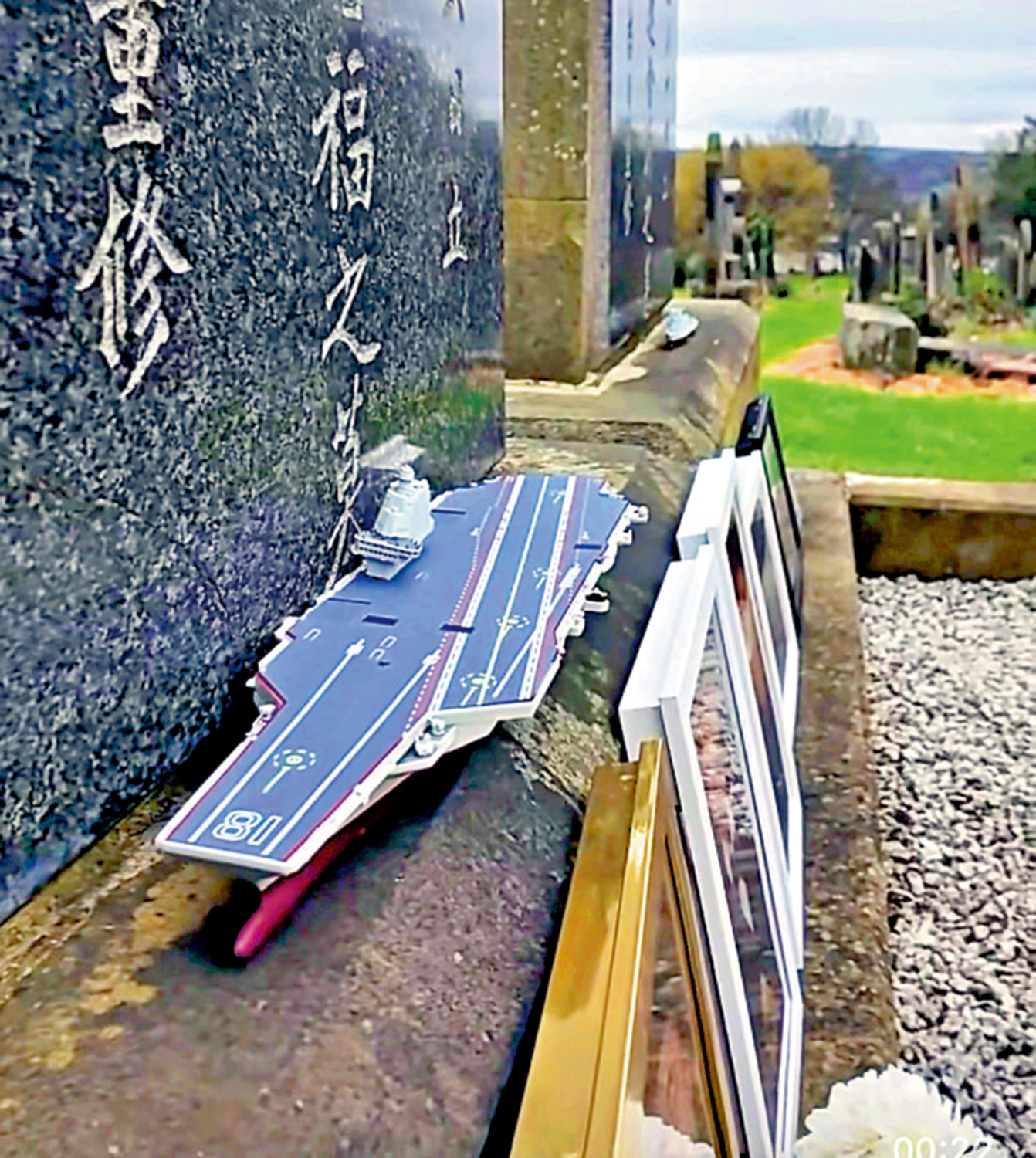 　　圖：參加祭掃人士在墓碑前方放着中國航母模型，告慰長眠英國的北洋水師水兵。