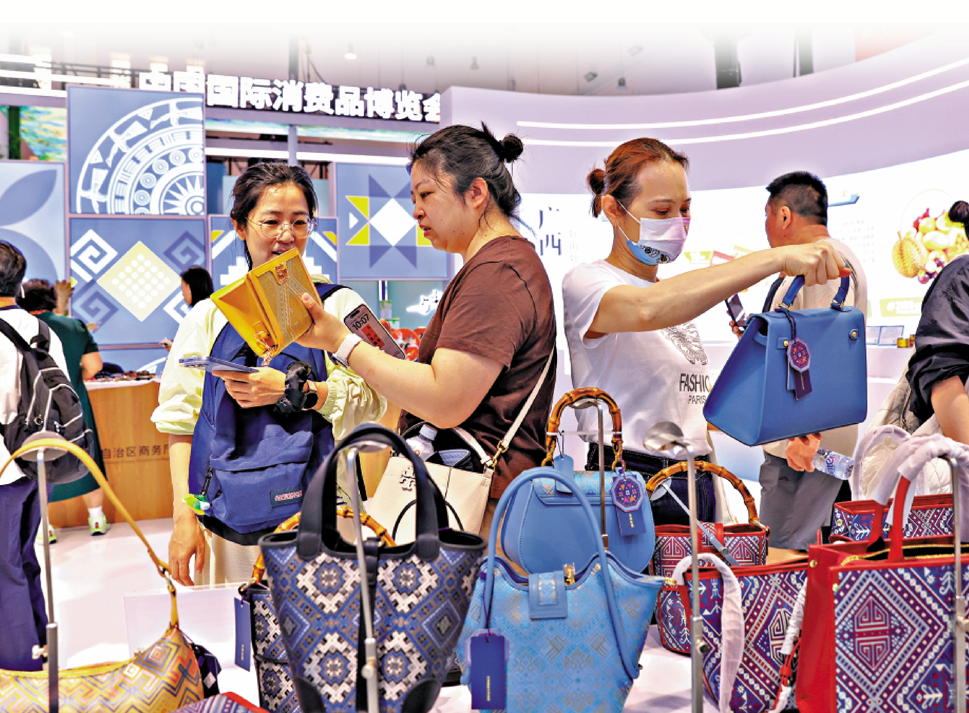 　　圖：4月17日，海南海口，參觀者在消博會廣西展區選購壯錦包。\中新社