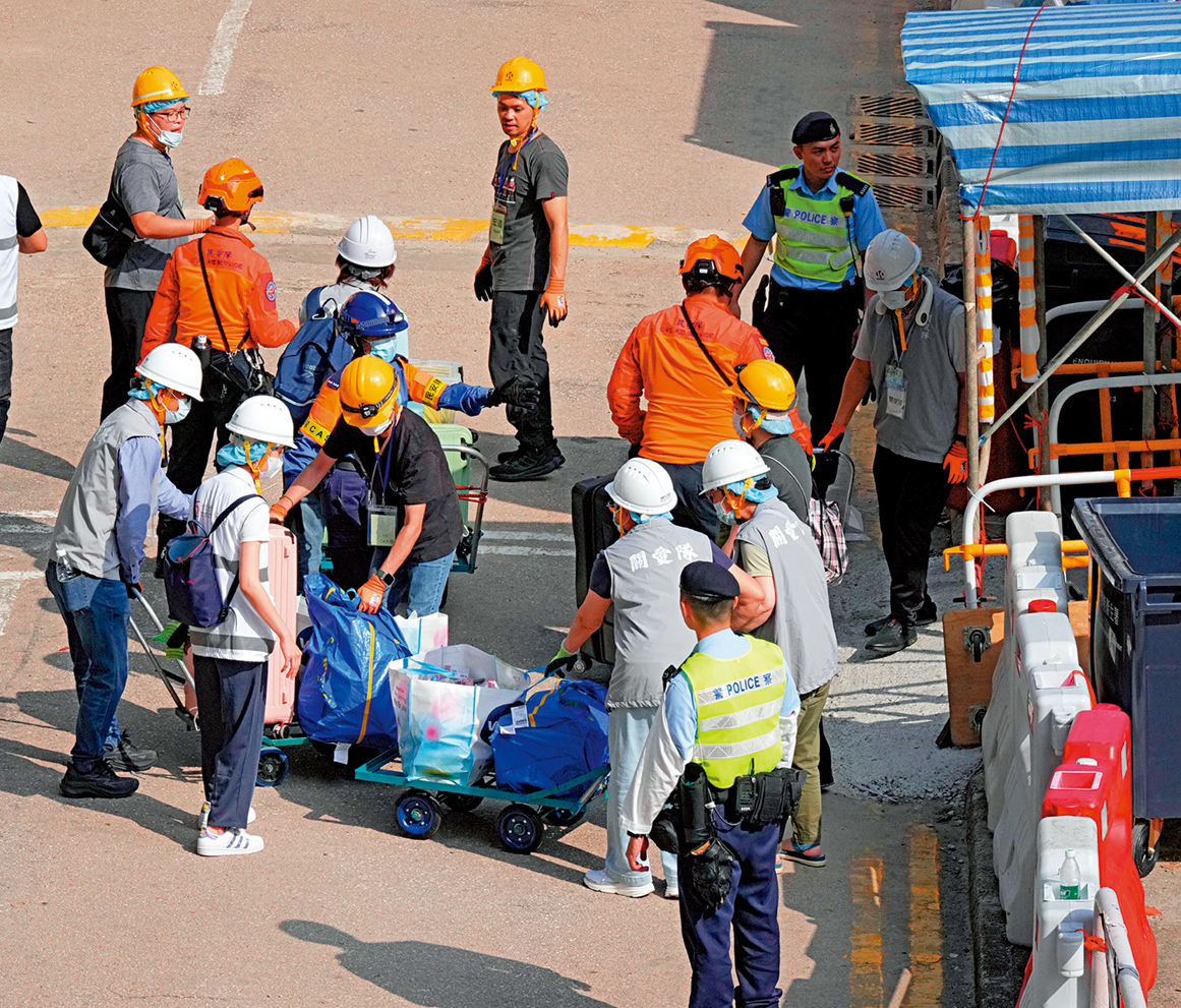 　　圖：關愛隊、民安隊及政府人員每日進駐宏福苑，全方位協助居民上樓執拾。\大公報記者林良堅攝