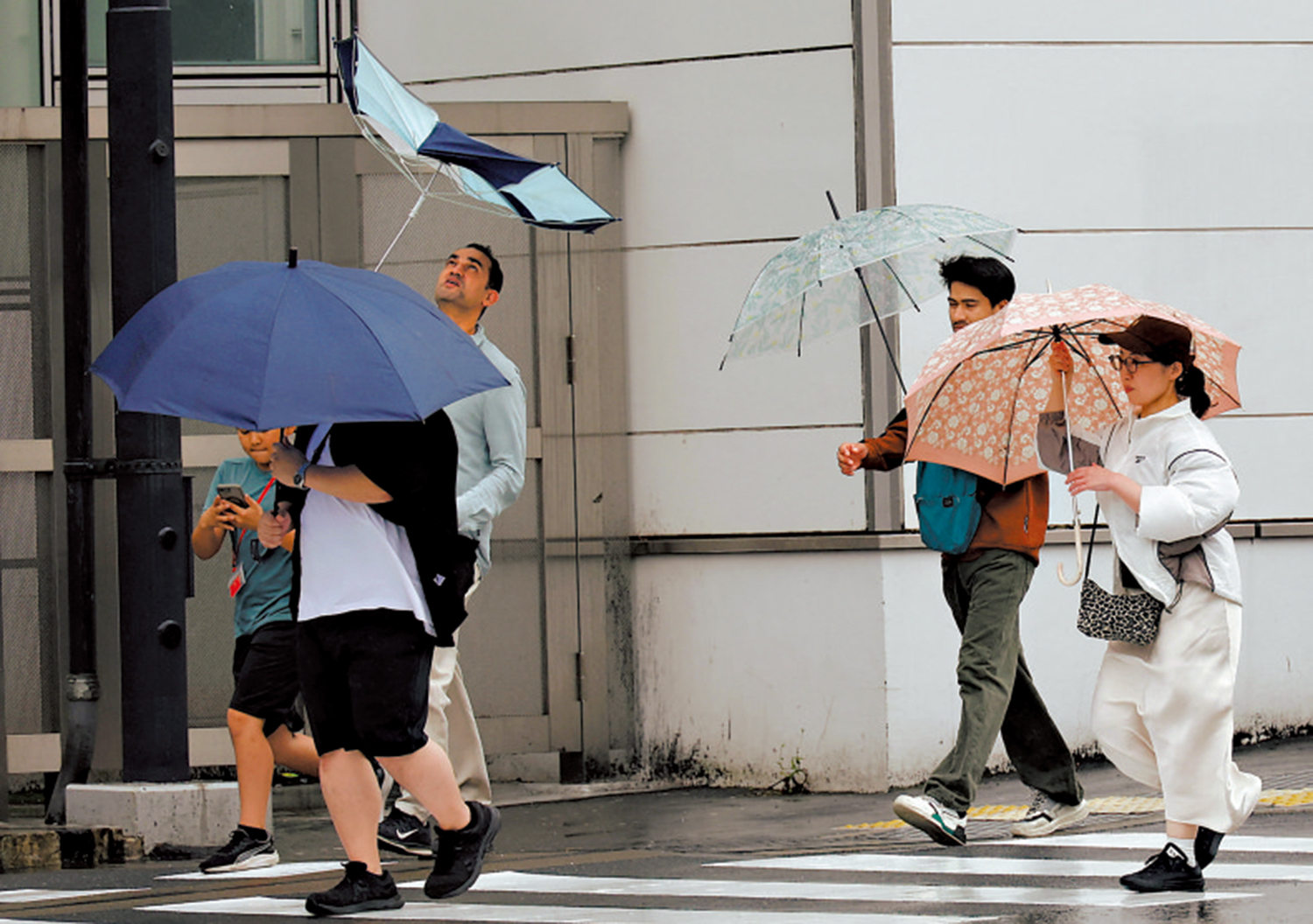 　　圖：日本東京27日下雨，行人的雨傘被吹翻。\路透社