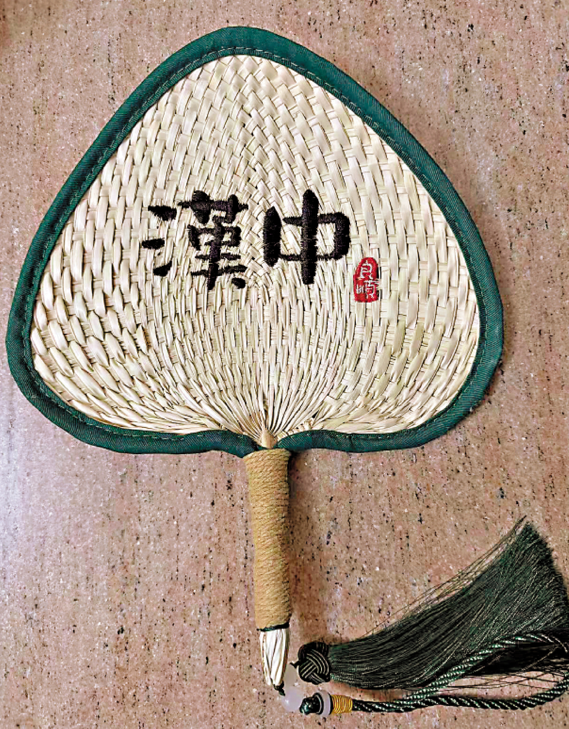 　　圖：用黑線繡有「漢中」二字的竹編扇子。\作者供圖