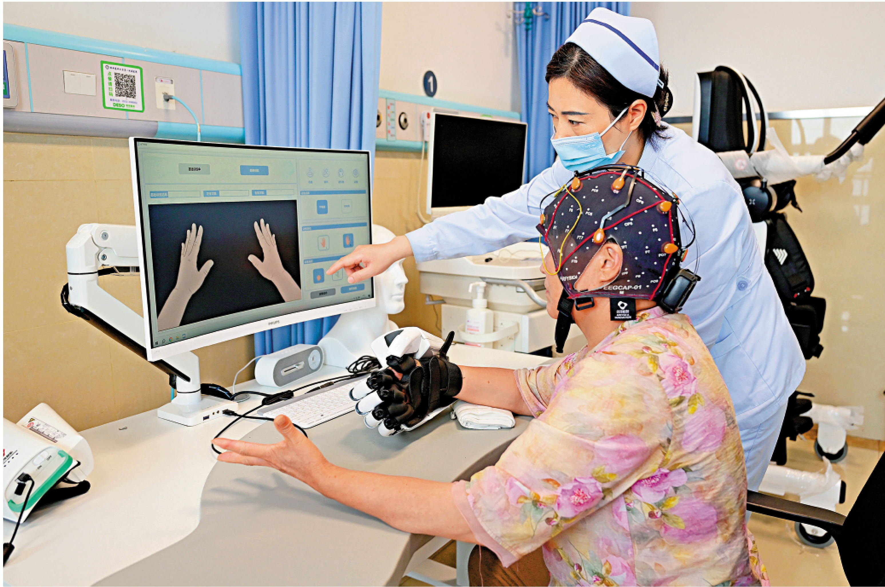 　　圖：7月17日，醫務人員指導患者用腦機接口設備進行手部康復訓練。\新華社