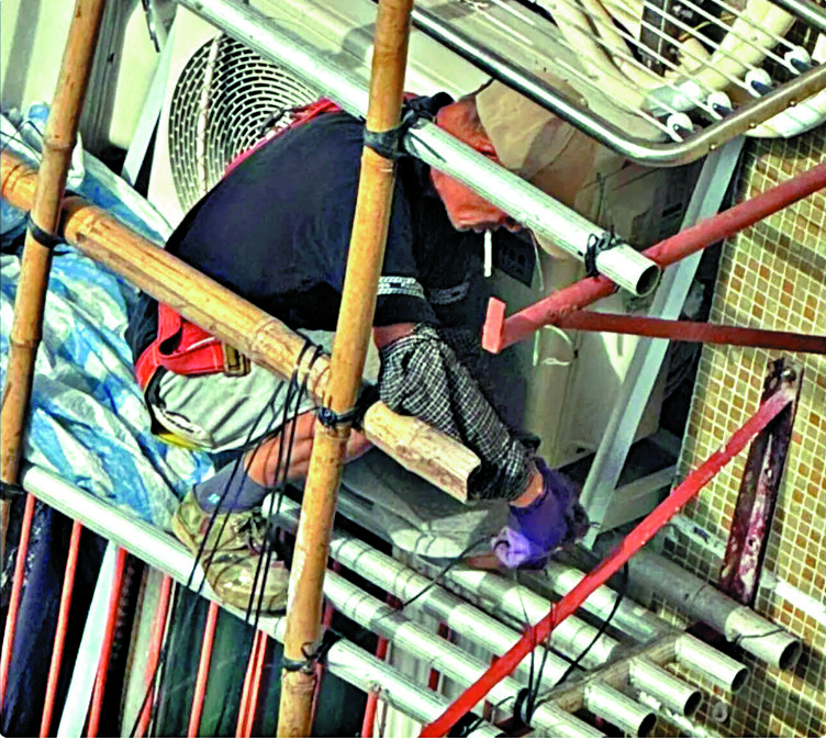 　　圖：竹園南邨有男工被揭發在棚架上吸着煙開工。\網上圖片