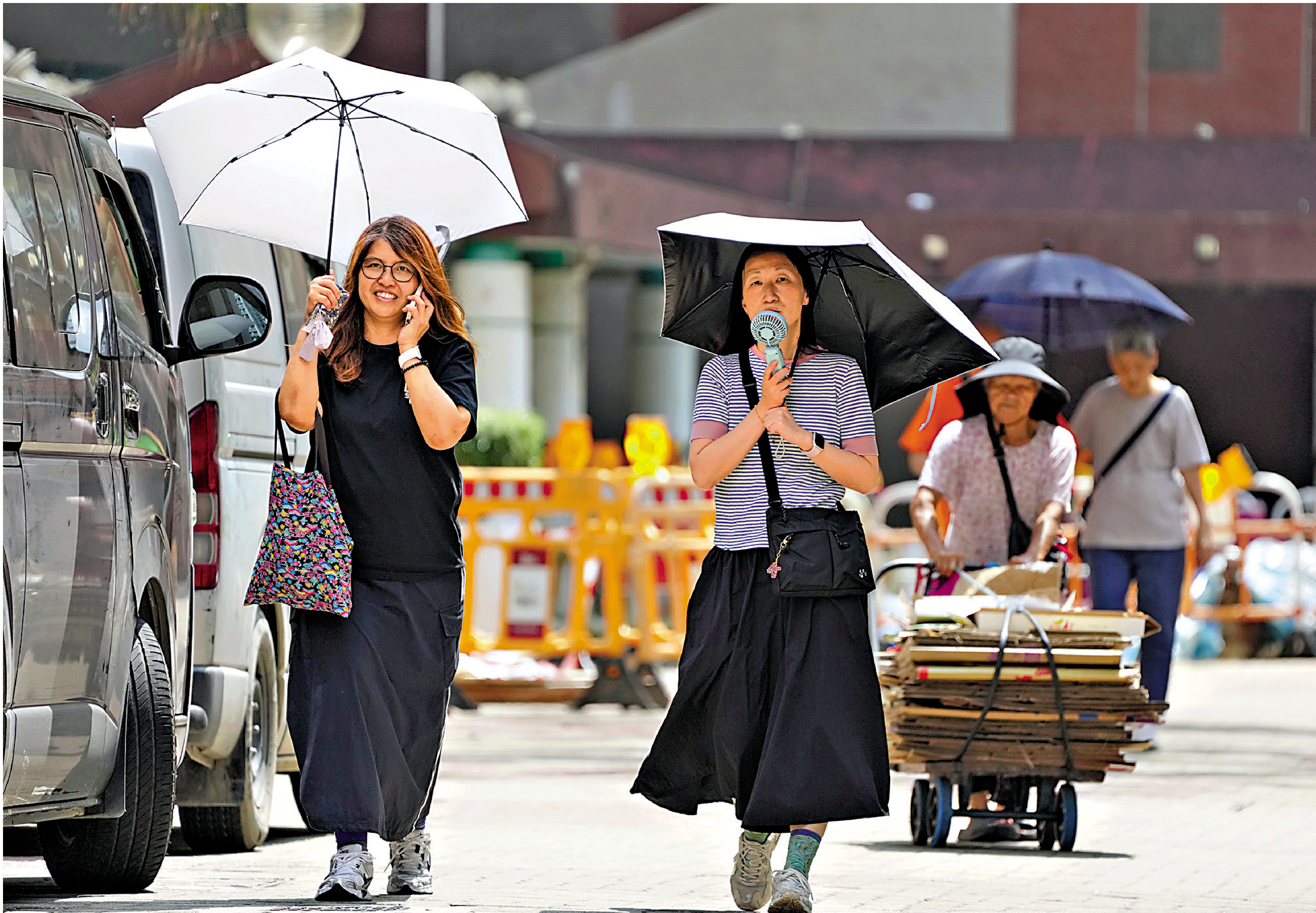 　　圖：有市民在烈日下舉傘遮擋陽光，預料今明有驟雨。\大公報記者何嘉駿攝