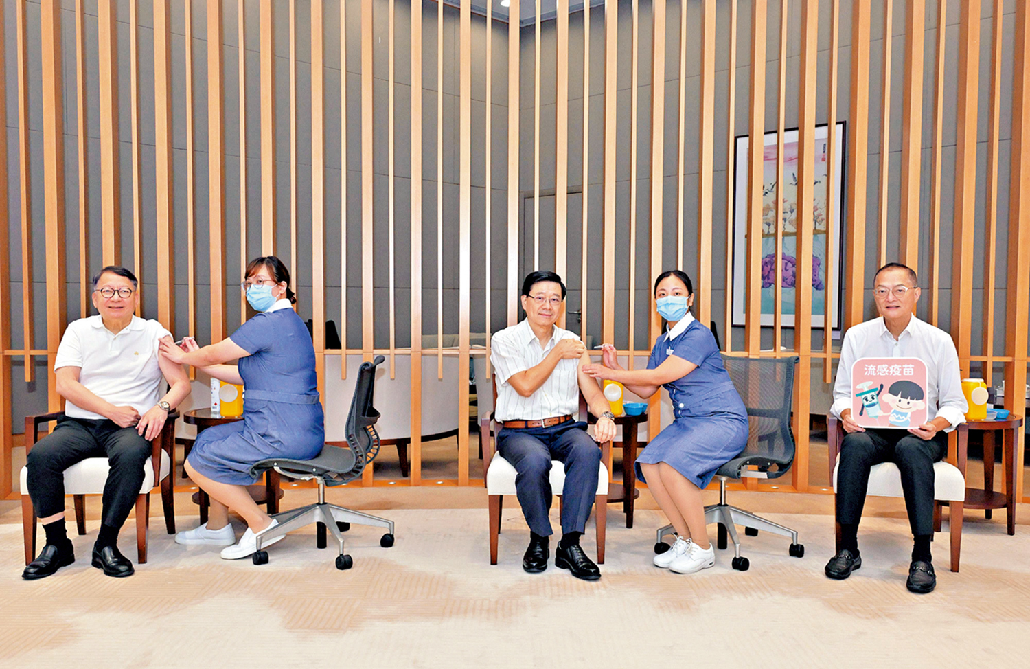 　　圖：行政長官李家超和政務司司長陳國基，在醫務衞生局局長盧寵茂陪同下接種疫苗。\政府新聞處