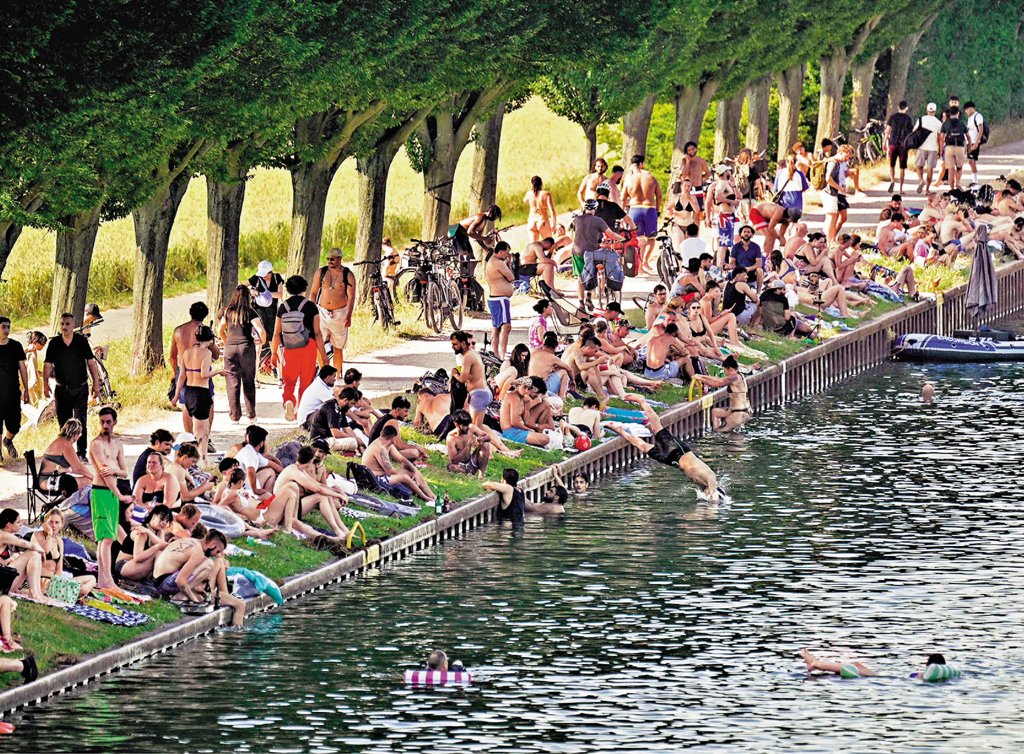 　　圖：6月26日，德國多特蒙德居民在埃姆斯運河畔納涼。\法新社