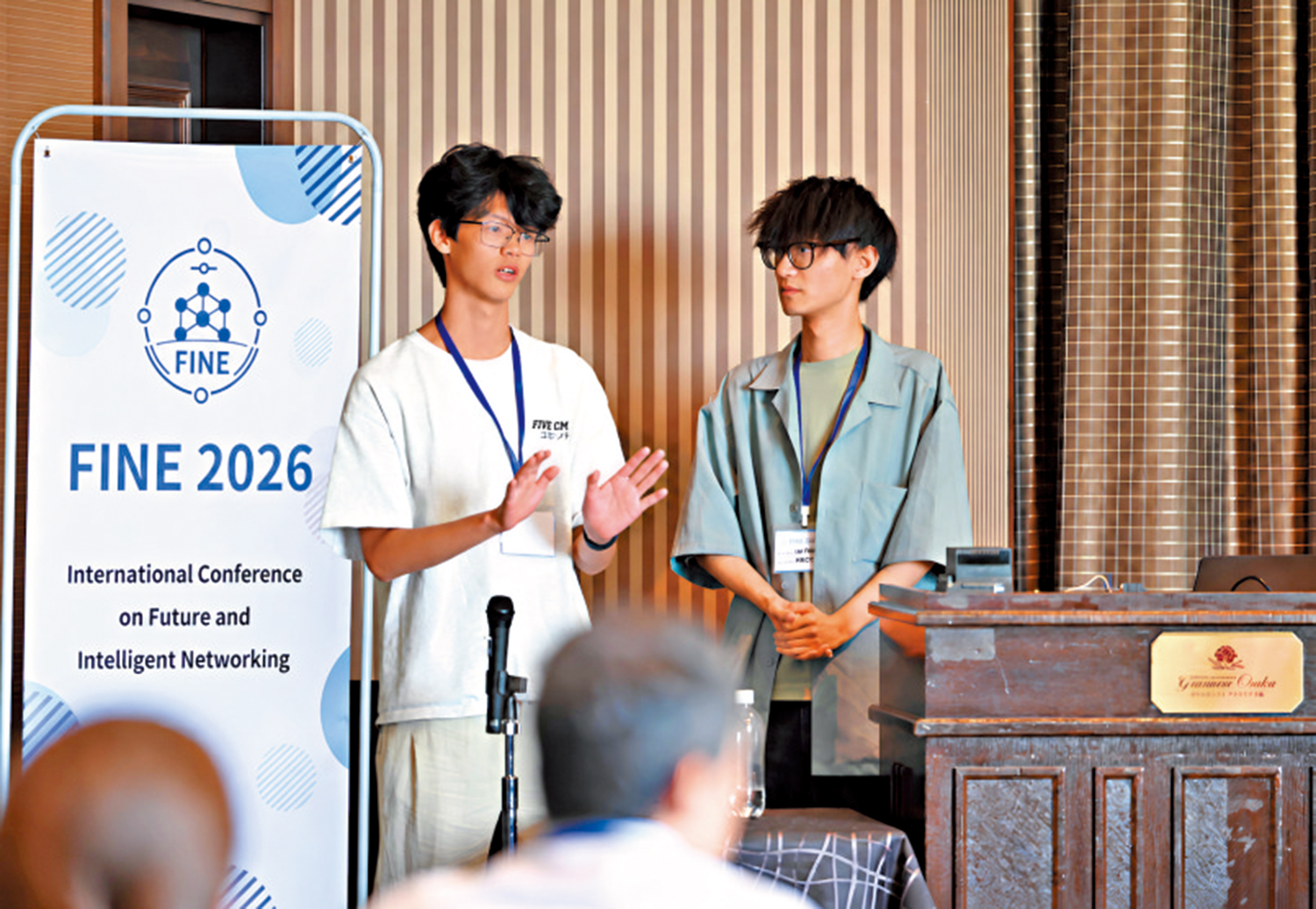 　　圖：兩名港專學生在大阪會議上介紹自主研發裝置。\港專提供