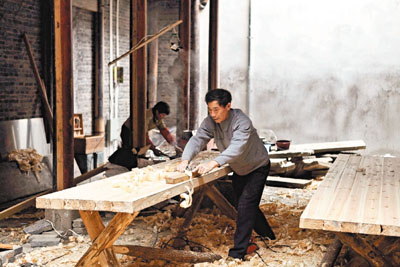 　■由於政府啟動「百村千幢」工程，大批本地工匠紛紛回鄉。圖為一名工匠使用傳統工具為木料刨光。