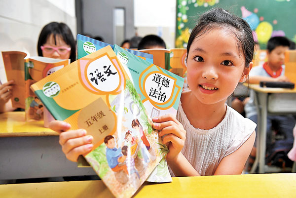 ■教育部日前出台一系列教材管理辦法。圖為福州一小學生展示發放的教材。 資料圖片