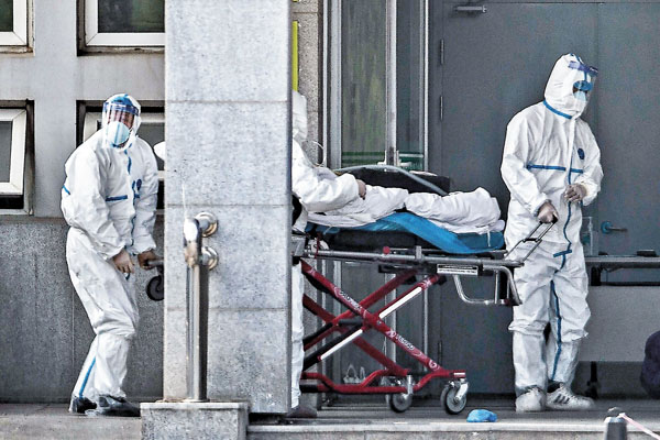 ■ 武漢3名全副防護裝備的醫護人員上周六將一名病人送進金銀潭醫院。 法新社