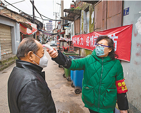 ■武漢市宣佈7日起開展全民體溫監測。圖為西城壕社區網格員為居民測量體溫。 新華社