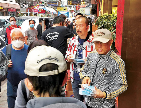 ■ 劉榮業（右一）與弟弟劉榮輝（右二）義派口罩給長者及街坊。