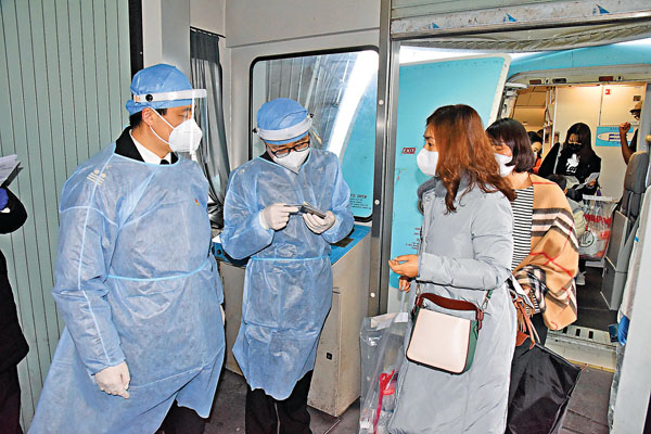 ■ 內地已全面要求所有出入境人員必須進行健康申報。圖為工作人員在青島流亭國際機場廊橋口檢查旅客證件。 新華社