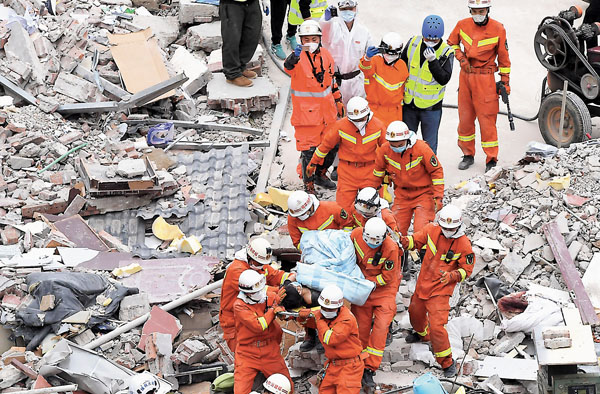 ■ 昨日16時38分，現場救援人員救出第49名被困人員。據了解，獲救的女子為當天11時24分左右救出的12歲男孩的母親。男孩在獲救後說的第一句話就是：「媽媽在我腳下，還活�荂I」圖為男孩母親被救援人員抬出事故現場。 中新社