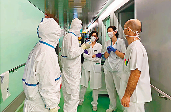 ■在感染科病區，中國專家組（�茈�套防護裝備）與當地病房醫護人員（�茧u袖裝）交流。 香港文匯報浙江傳真