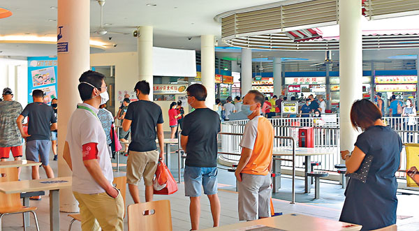 ■ 熟食中心有檢查員（左3）督促大眾保持社交距離。美聯社