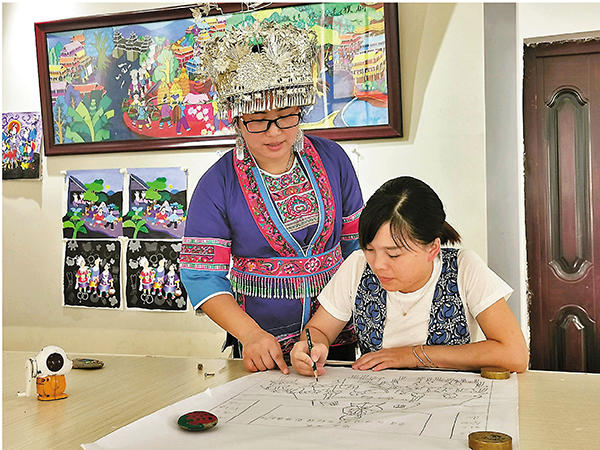 ■吳凡宇（左）向周邊的青少年傳授農民畫繪畫技巧。 香港文匯報記者曾萍  攝