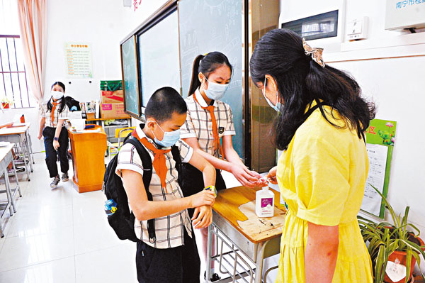 ■5月6日，廣西南寧市、河池市等多地小學四至六年級學生返校上課。圖為桂雅路小學桂花校區的學生進行手部消毒。中新社
