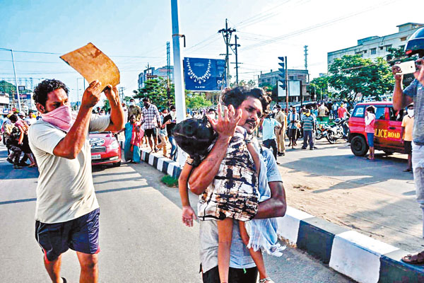 男子抱�茷警ㄩM離，一旁的村民用卡紙送風。 法新社