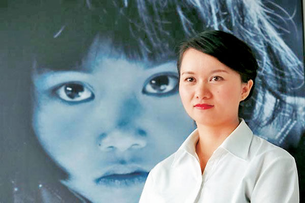 ■蘇明娟1991年被拍下一張後被希望工程徵用的照片。圖為蘇明娟2017年站在該照片前。 資料圖片